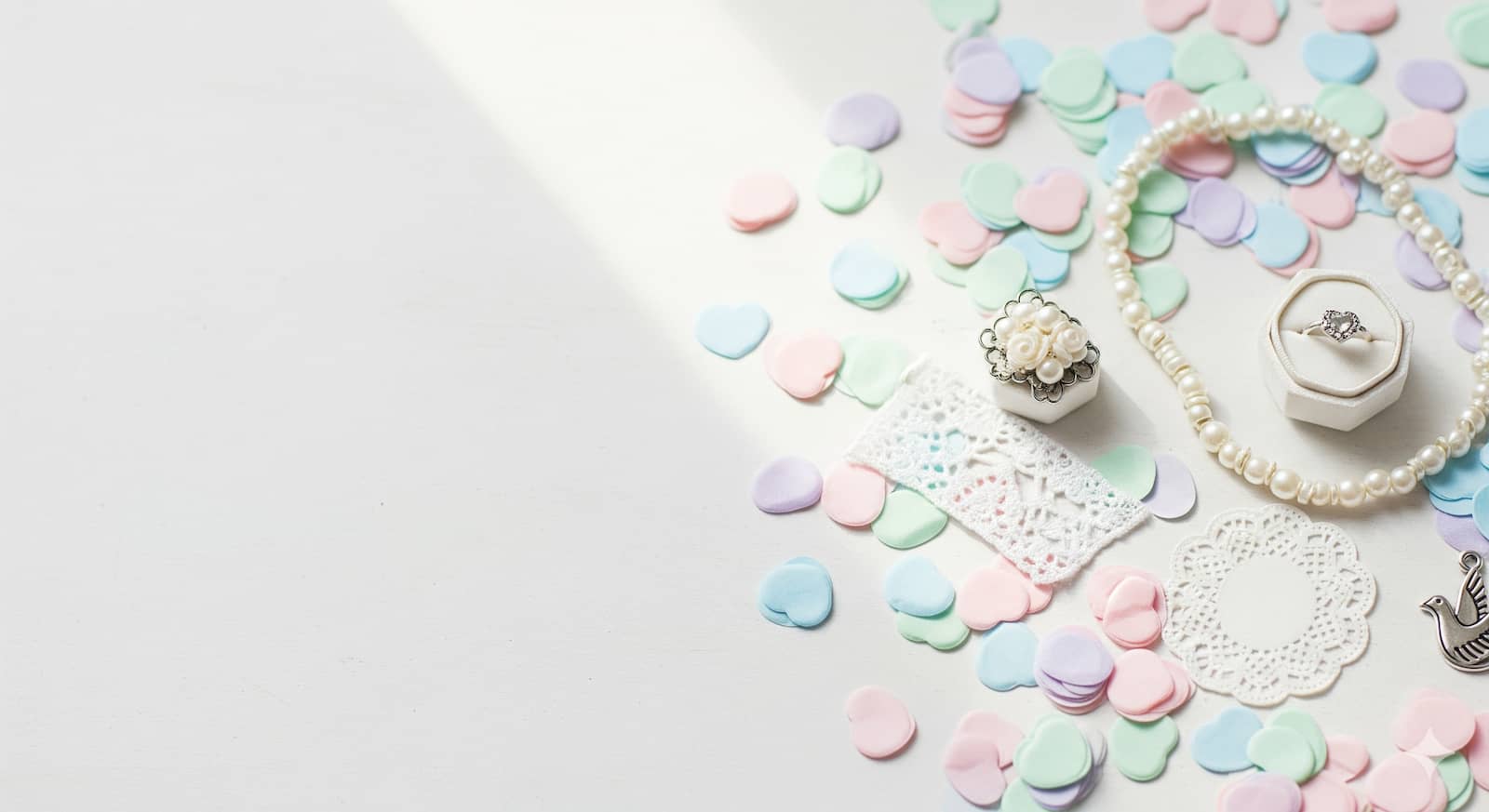 Pastel confetti hearts and small wedding trinkets flat lay
